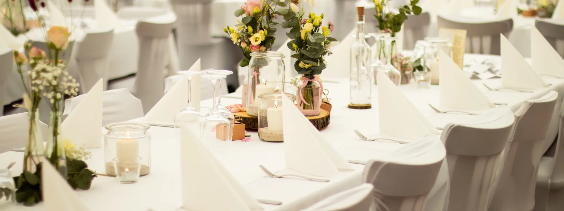 Festlich eingedeckte Hochzeitstafel mit weißen Hussen, Blumen und Kerzen im Langenhorster Hof